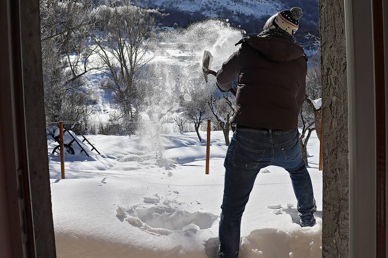 Un joven quita la nieve de la puerta de su casa.