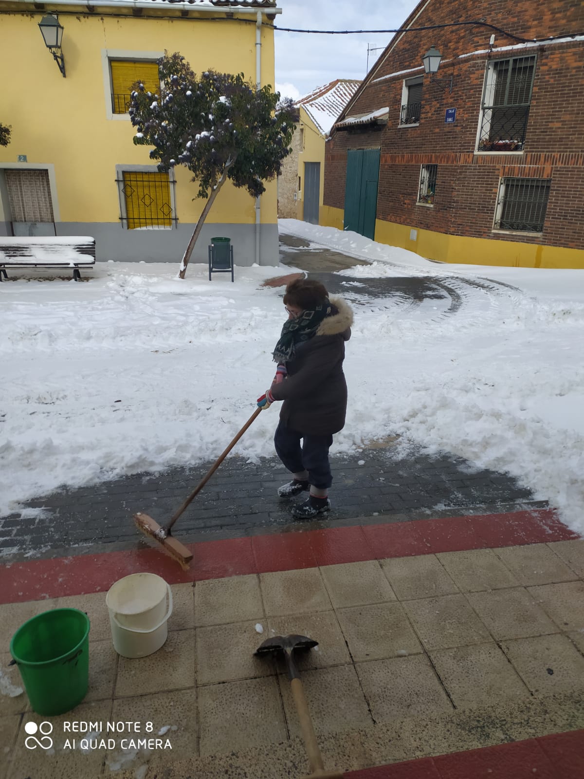 La alguacil de Castrodeza eliminando el hielo de la puerta del Ayuntamiento.