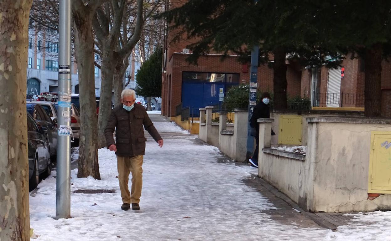 Un hombre camina con tiento por la acera congelada de la calle Hernando de Acuña. 