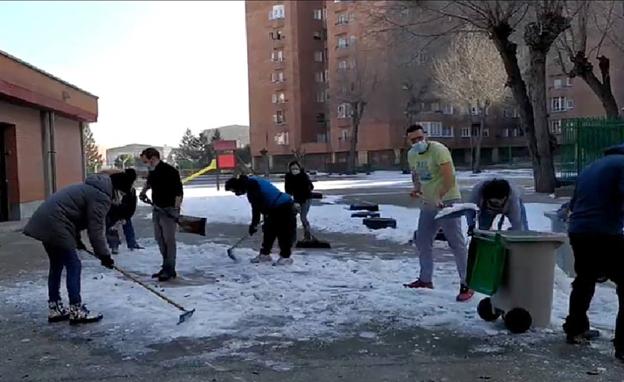 Padres y madres del colegio Vicente Aleixandre retiran el hielo del patio.