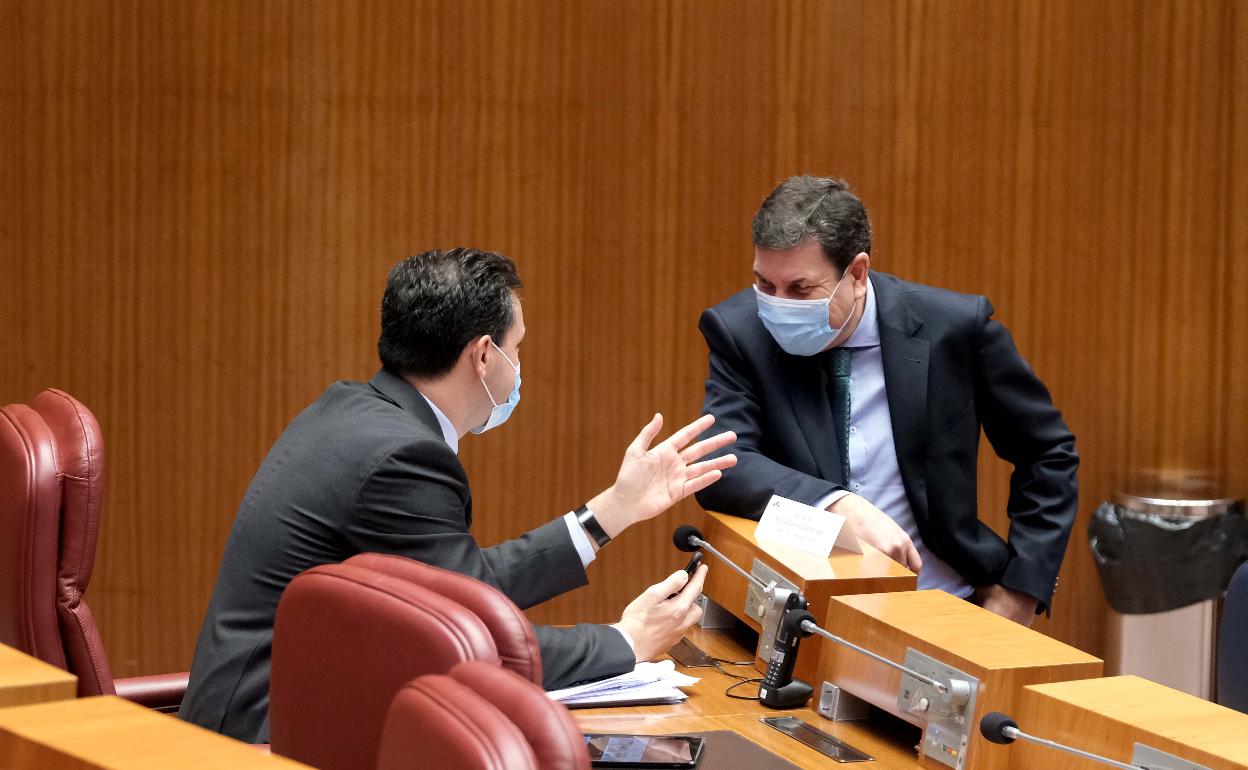 Carlos Fernández Carriedo, consejero de Economía y Hacienda, conversa en el hemiciclo con el portavoz del PP en las Cortes.