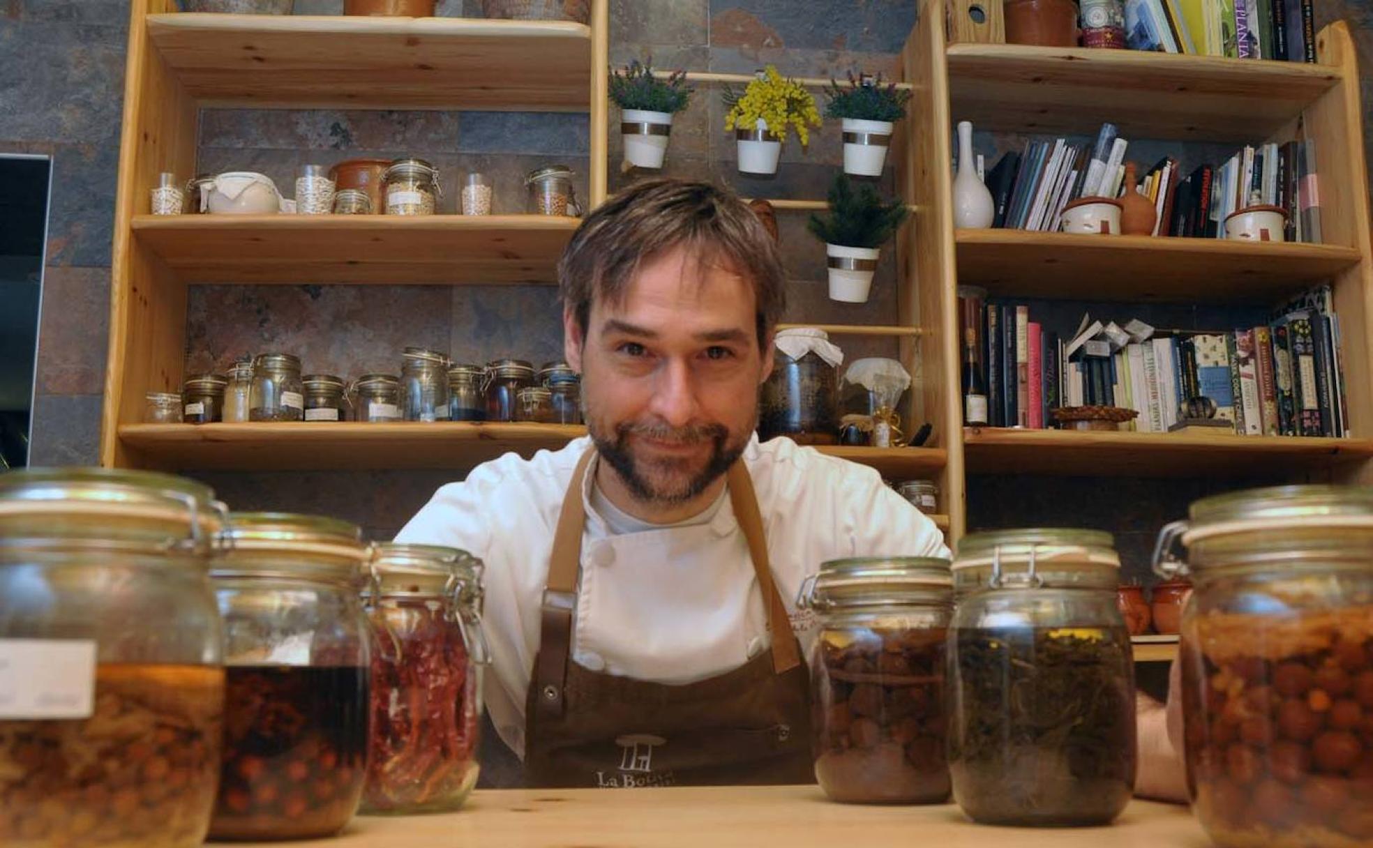 Miguel Ángel de la Cruz posa con algunos de los tarros que prepara el propio chef con plantas, vegetales, frutas, legumbres y piñas verdes de pino piñonero. 