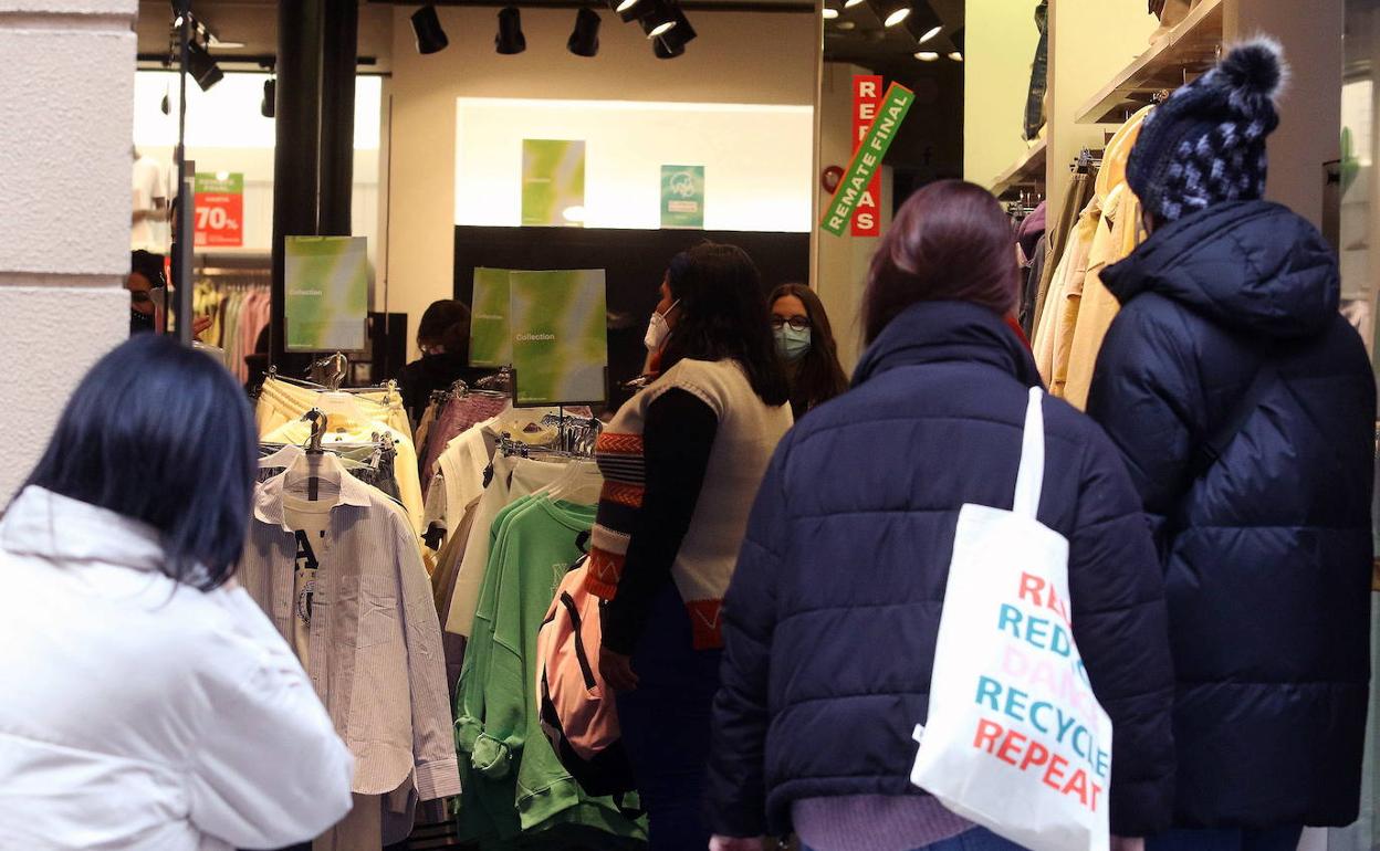 Varias personas esperan a entrar en una tienda de ropa en Segovia. 