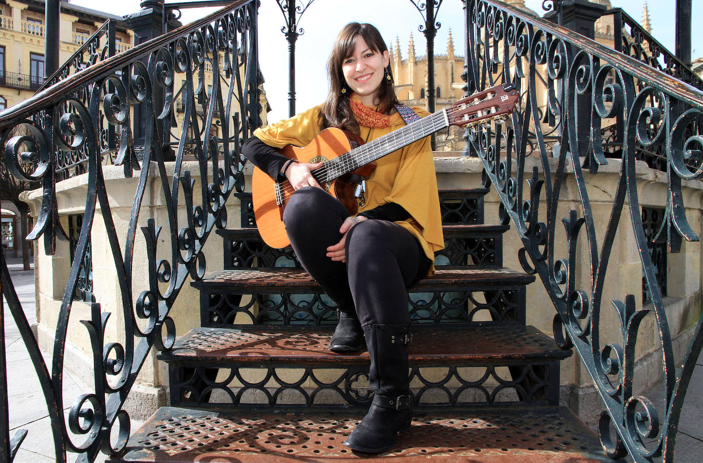Marta Revuelta posa sentada en las escaleras del quiosco de la Plaza Mayor de Segovia con su guitarra.
