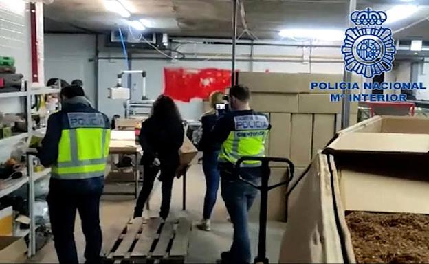 Policías y funcionarios registran el interior de la planta de producción de tabaco desmantelada.