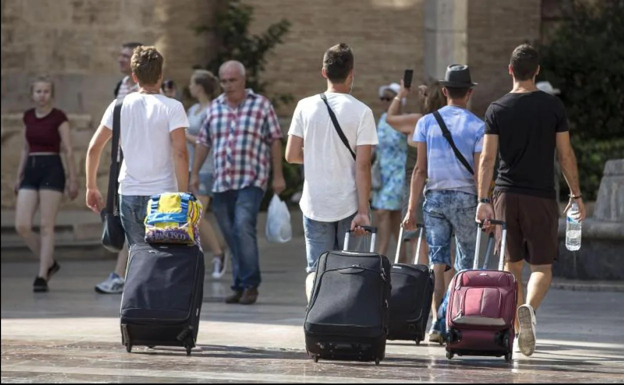 Cuatro jóvenes turistas caminan con su maletas.