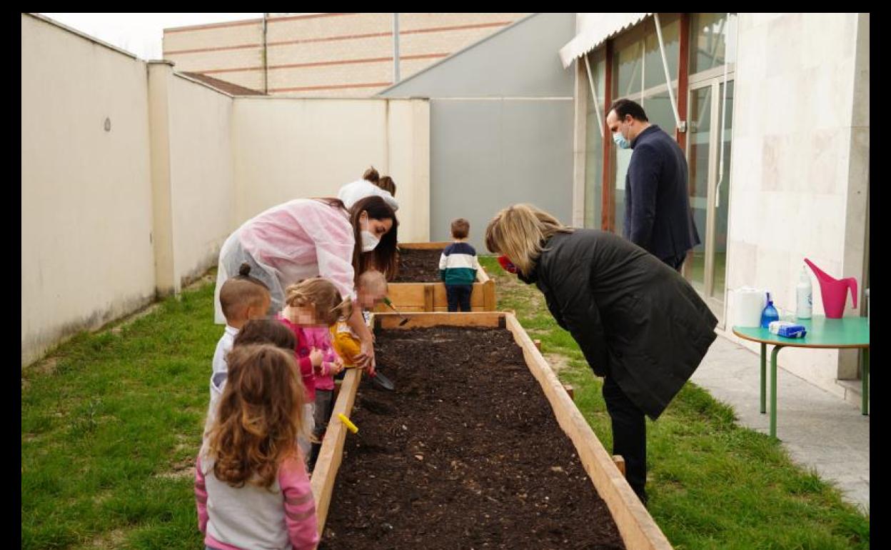 Los niños aprenden a cultivar ante la mirad del alcalde y la concejala.