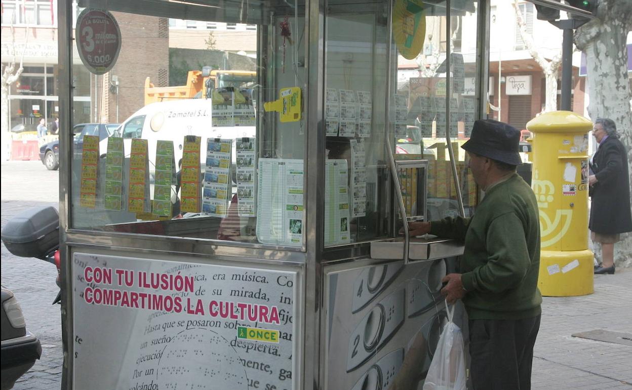 Una persona compra un cupón en un quiosco de la ONCE