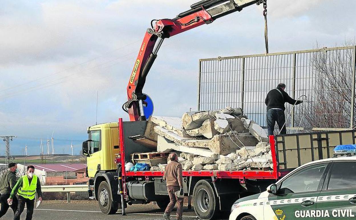 Los operarios del camión retiran la carga caída en la calzada.