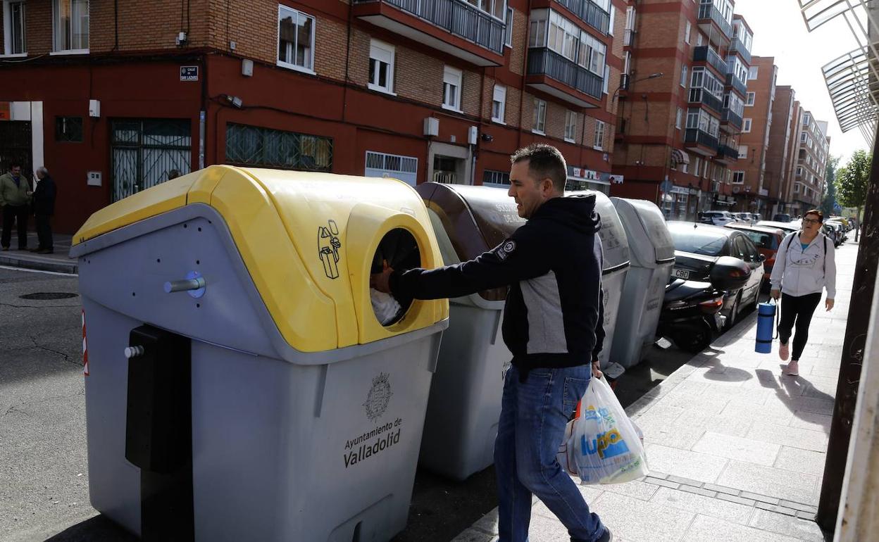 Un hombre deposita plástico en un contenedor amarillo en la calle Júpiter. 