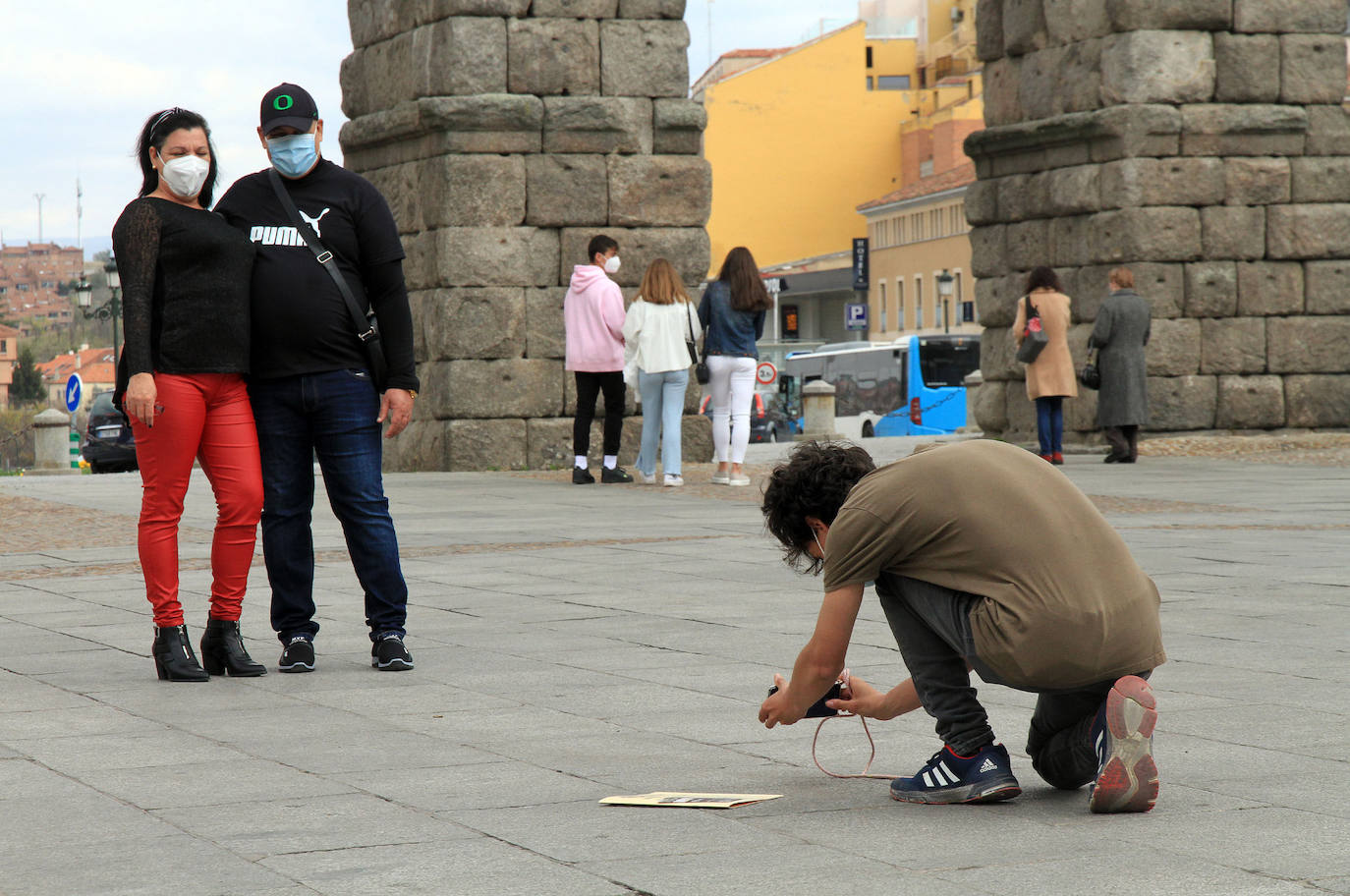 Un hombre fotografía a una pareja en la plaza del Azoguejo.