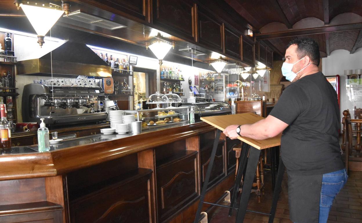 Un hostelero de Aguilar recoge mesas en el interior de un bar.