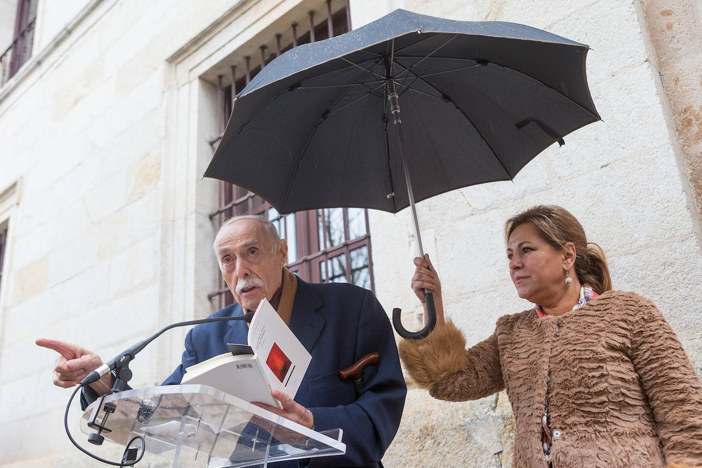 El poeta Jesús Hilario Tundidor recita poemas mientras la alcaldesa de Zamora, Rosa Valdeón, le cobija con su paraguas, durante el homenaje recibió en Zamora en 2014.