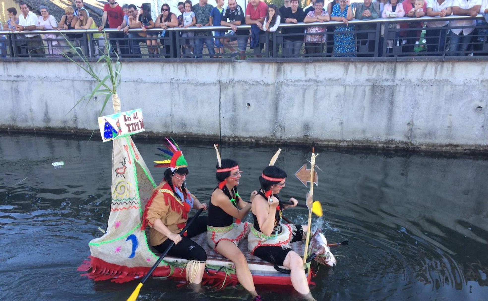 Una de las barcas con todos su tripulantes disfrazados que descienden por el río durante las fiestas de la Soledad de Camponaraya.