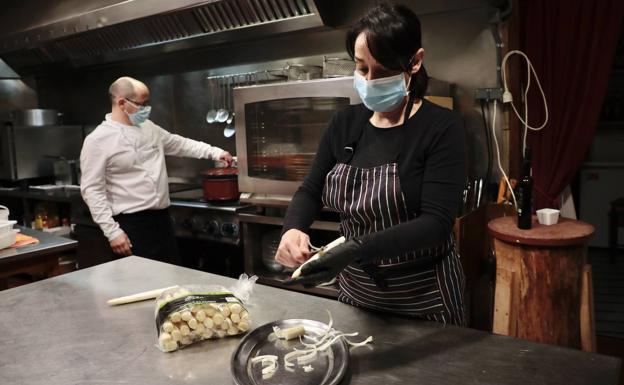 Imagen principal - La cocinera Ana García, del Mesón 2,39, de Tudela de Duero, pela espárragos, antes de prepararlos cocidos con vinagreta y crudos en carpacho. 
