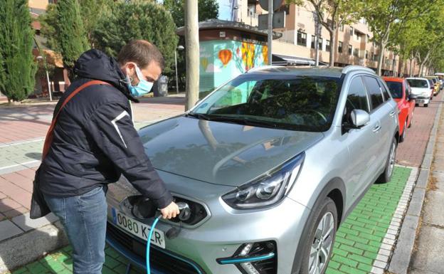 Juan González carga su Kia Niro en un poste eléctrico.