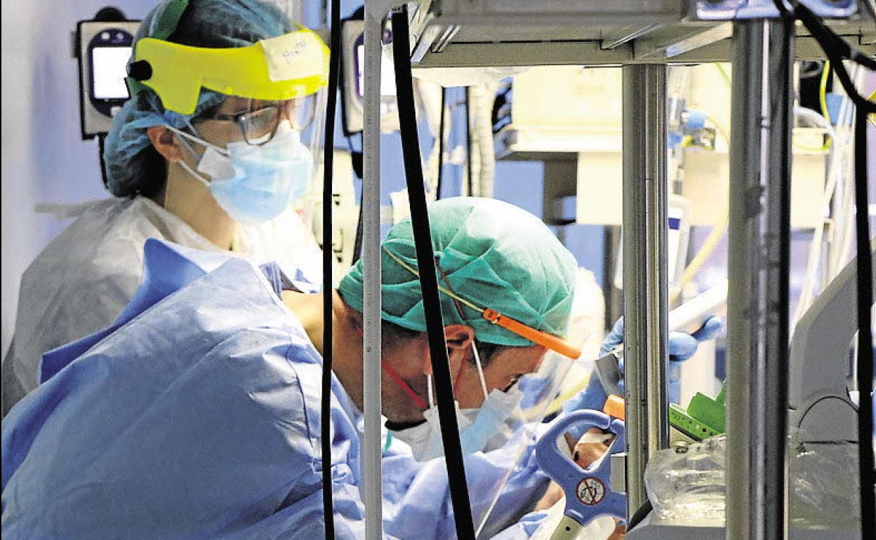 Dos sanitarios atienden a un paciente en la UCI del Hospital Clínico