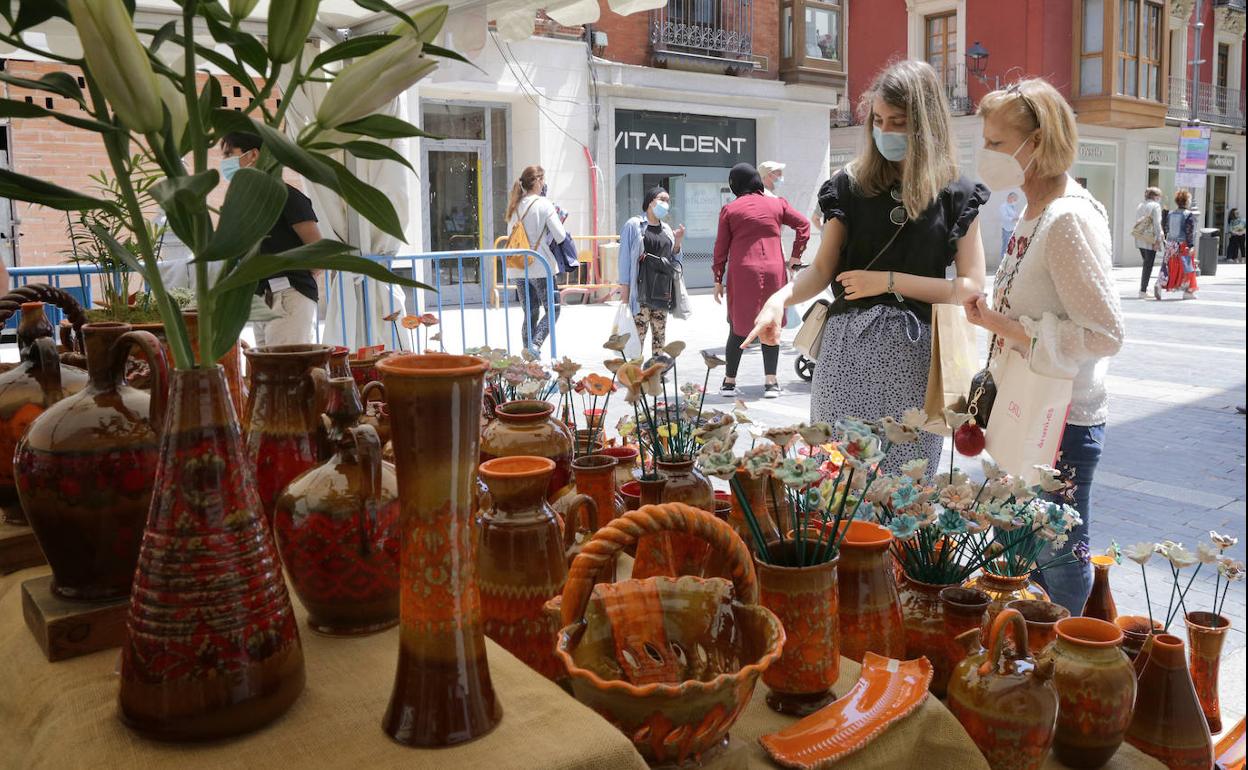 Dos mujeres contemplan la muestra de cerámica en la Calle Mayor.