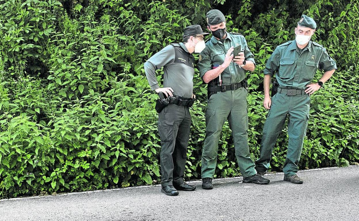 Agentes de la Guardia Civil observan las manchas de sangre en la carretera tras el ataque de un oso a una anciana en Asturias. 