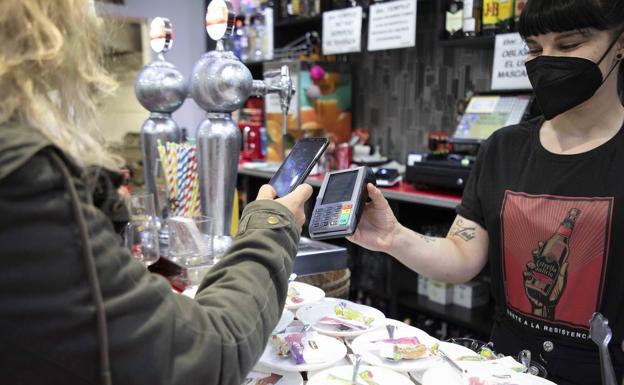 Una mujer paga con su teléfono móvil en el bar El Templo, en la calle Madre de Dios. 