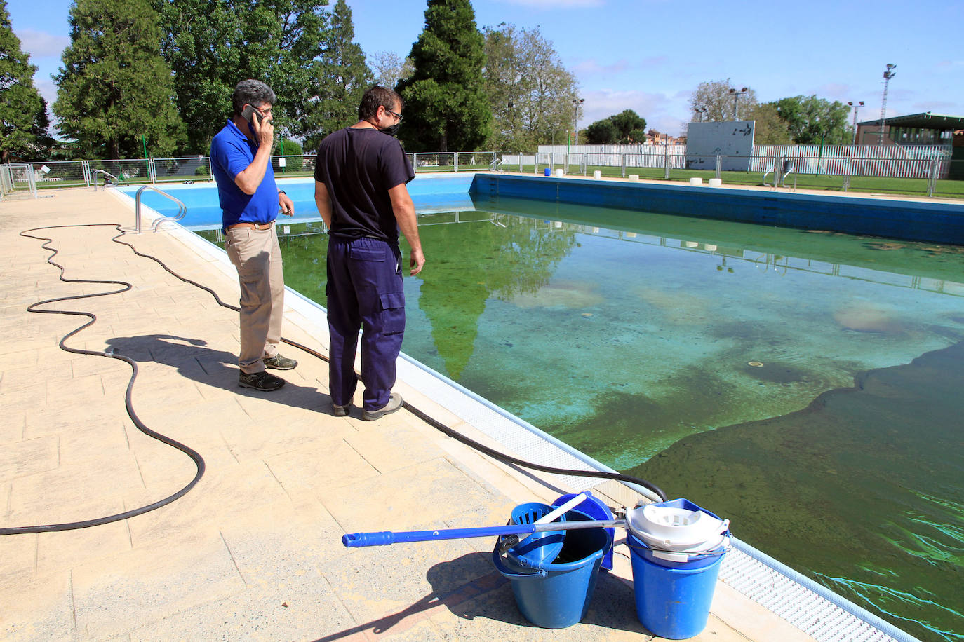 Operarios municipales trabajan en el vaso de la piscina de Segovia, aún sin vaciar.