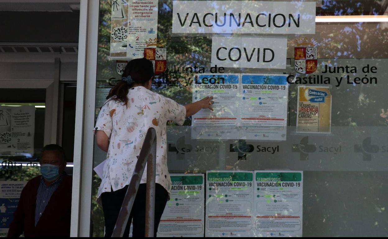 Una sanitaria del centro de salud de Santo Tomás, en Segovia, coloca carteles con los llamamientos a la vacunación contra la covid. 