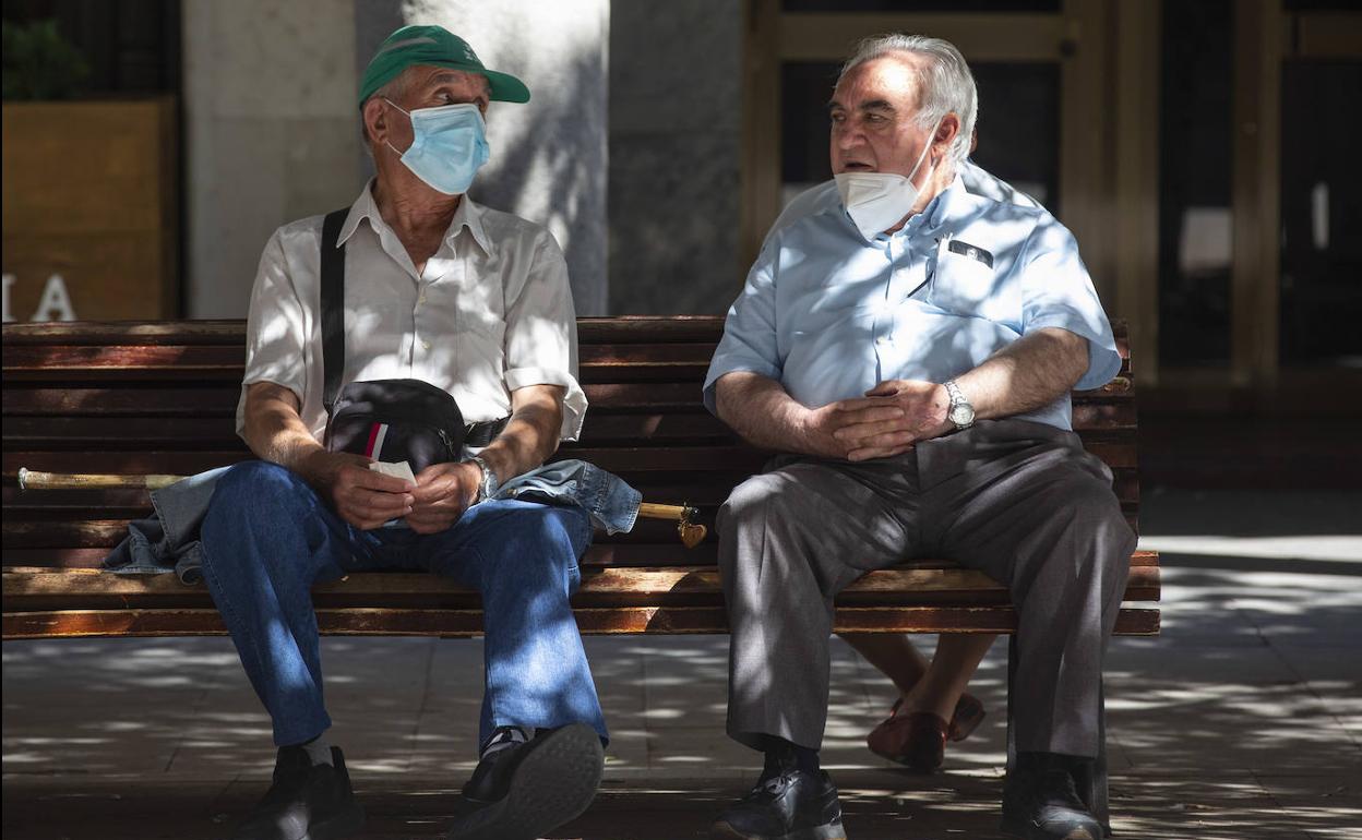 Dos hombres conversan en una calle de Valladolid durante la mañana del primer día en que la mascarilla dejó de ser obligatoria en la calle.