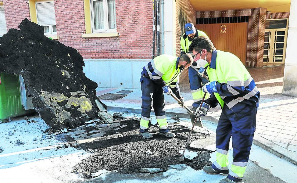 Operarios de Urbaser limpian los restos de un contenedor amarillo.