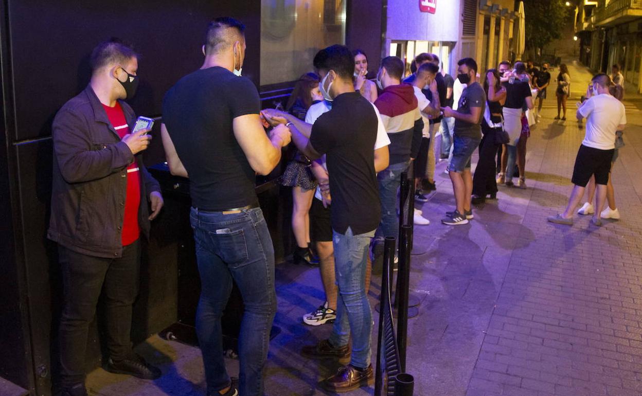 Varios jóvenes a la puerta de un local de ocio nocturno. 