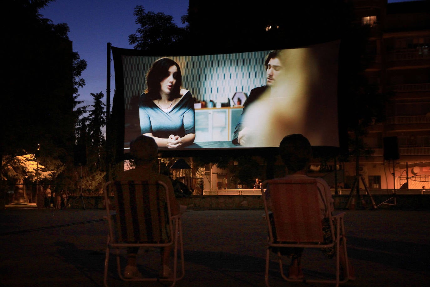 Dos mujeres ven una película, este viernes, en el cine de verano del barrio de La Albuera.