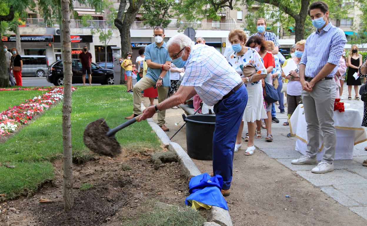 Un vecino echa una palada de tierra sobre el árbol recién plantado en el parque en homenaje a las víctimas del barrio.