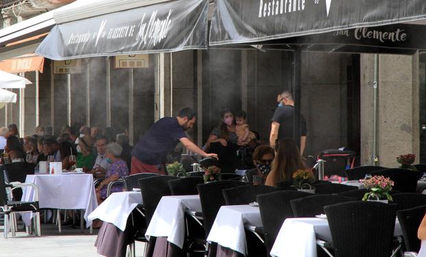 Imagen principal - Arriba, terraza provista de un toldo que lanza agua pulverizada. Abajo, izquierda, transeúntes por la Calle Real de Segovia en la mañana de este domingo, y a la derecha un termómetro que marca 33º. 