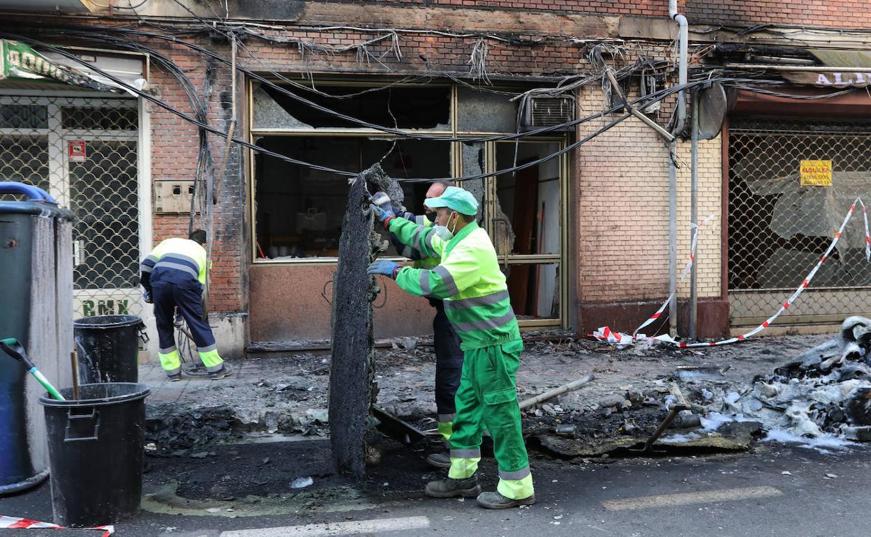 Los operarios recogen los contenedores quemados. 