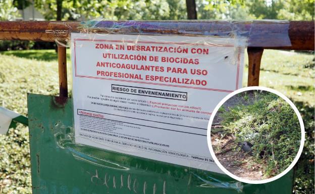 Imagen del cartel que avisa de la presencia de biocidas y uno de los cebos escondidos, en forma de caja negra, entre los arbustos.