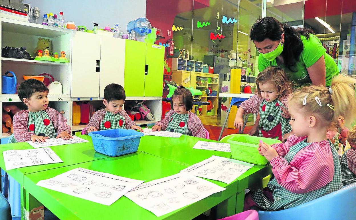 Un grupo de niños de El Gusanito se dispone a pintar una ficha con su profesora Adriana. 