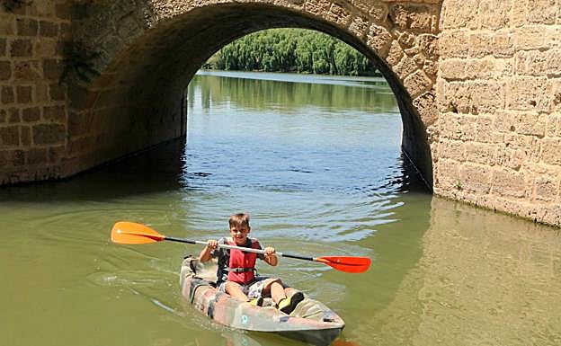 Imagen principal - Las piraguas se han convertido en un gran atractivo turístico de Torquemada en verano. Abajo, el monitor Humberto Brun realiza una demostración del manejo de las piraguas. 