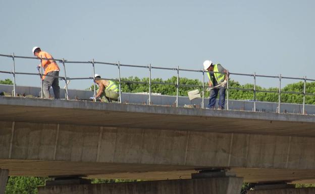 Tres operarios trabajan sobre un paso. 