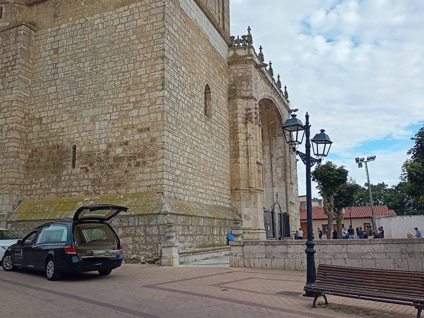 El coche fúnebre, en el exterior de la iglesia de la Asunción de Dueñas, esta tarde durante el funeral de la usuaria de la residencia de 92 años fallecida en el hospital. 