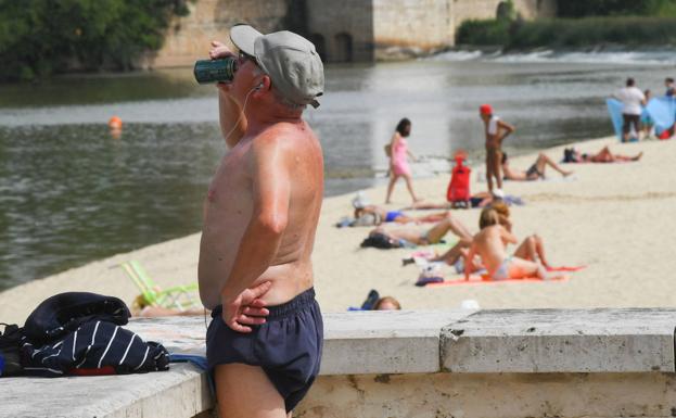 Personas toman el sol en la playa de las Moreras.