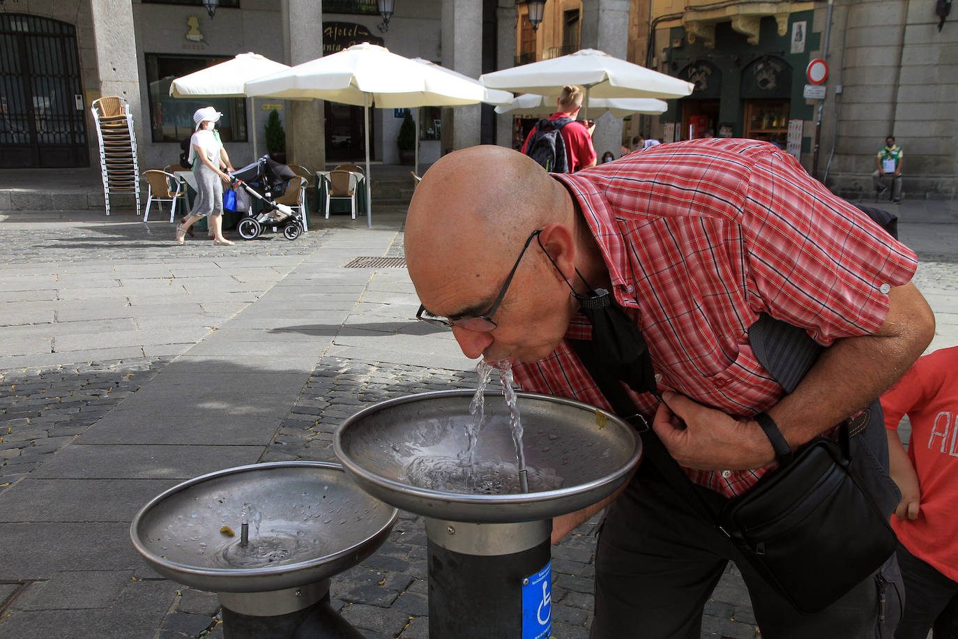 Un hombre bebe agua en la fuente de la Plaza Mayor. 