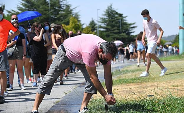 Galería. Un hombre se refresca en un aspersor.