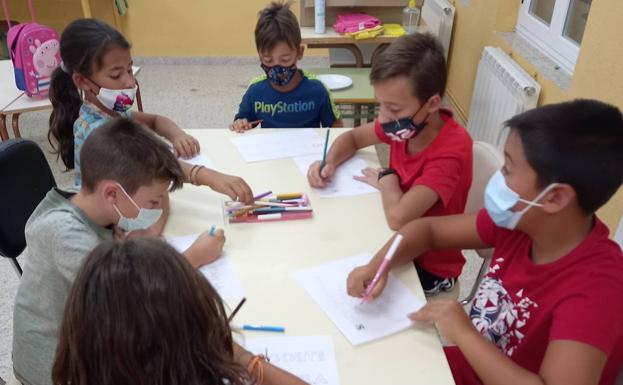 Imagen principal - Algunos de los niños realizando los carteles, que se colocaron en las inmediaciones de la escuela.