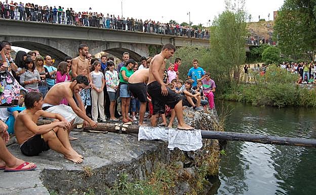 Un joven intenta no caerse de la resbaladiza cucaña.