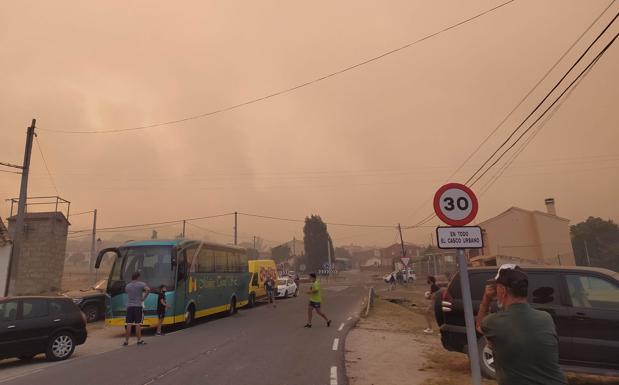 Imagen principal - Las autoridades han enviado autobuses para trasladar a los evacuados. Los vecinos han sacado sus tractores para empezar a hacer cortafuegos y evitar que las llamas lleguen al pueblo. Las cenizas del fuego han llegado a las casas de Ávila capital. 