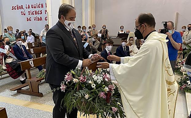 El alcalde entrega una cesta de flores en el ofertorio. 