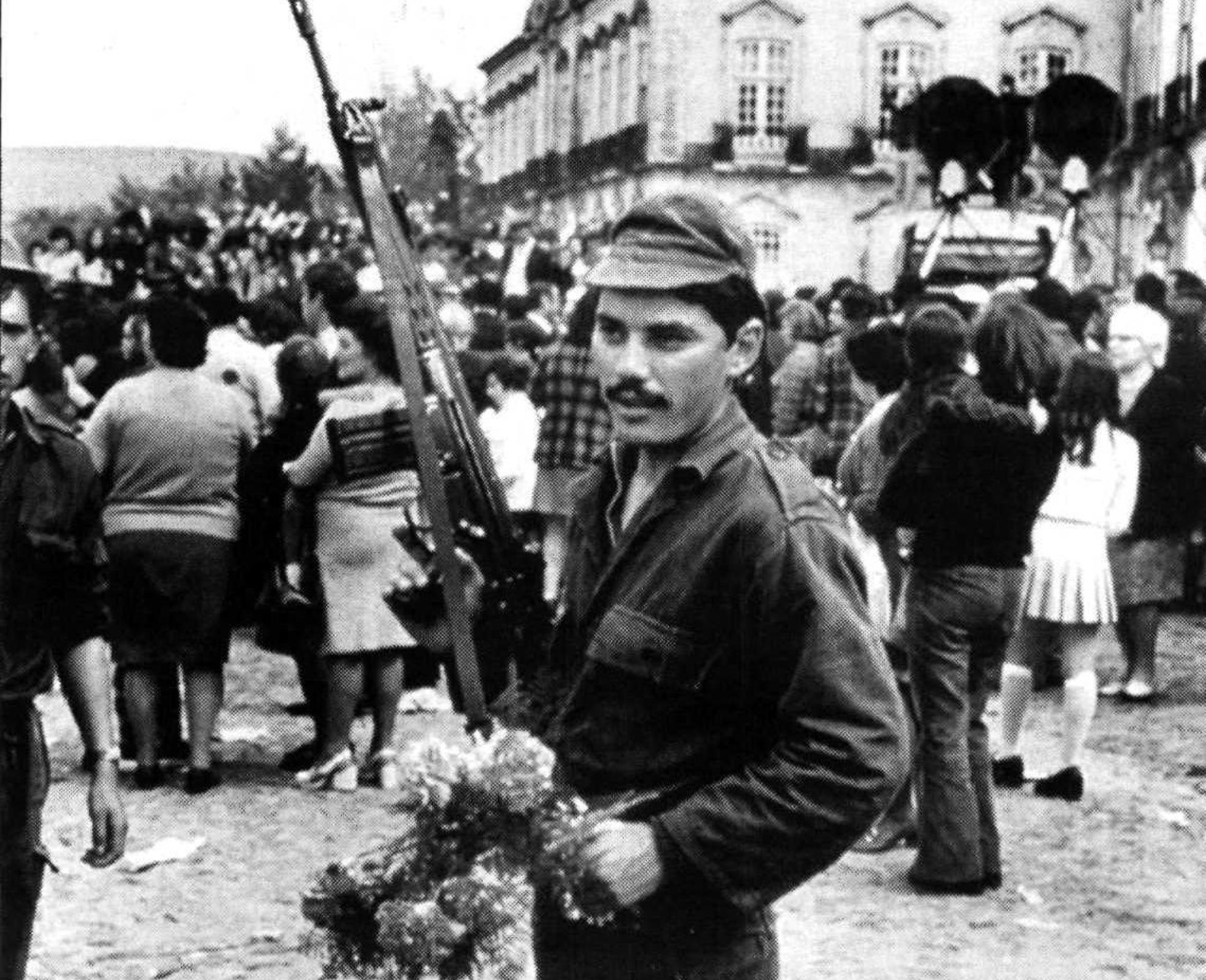 Un soldado portugués en la calle durante la revolución de 1974, con un fusil en la mano y los simbólicos claveles en la otra. 