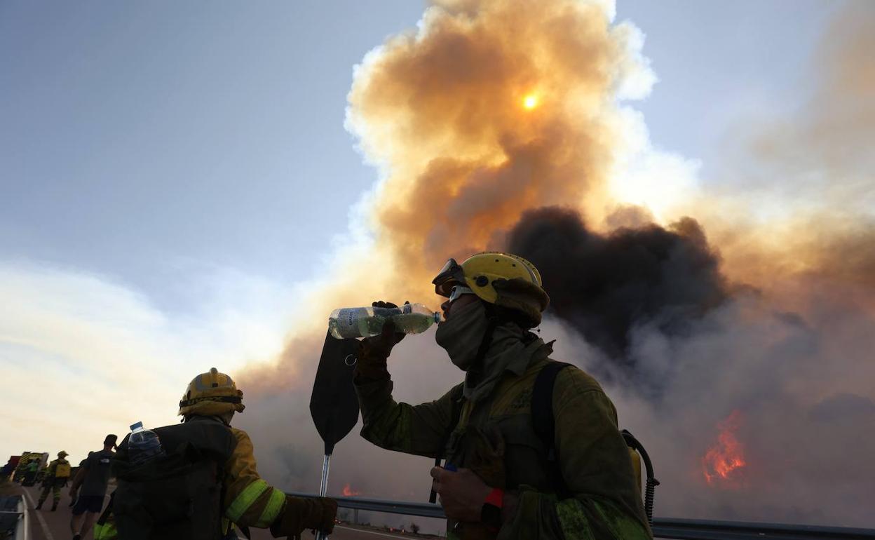 Un bombero se refresca en la zona del fuego.