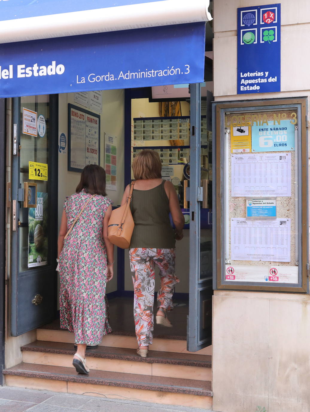 Dos mujeres entran en una administración de lotería. 