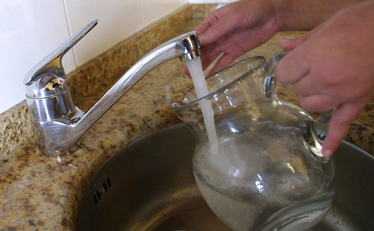 Un vecino llena una jarra con agua del grifo de su casa.. 