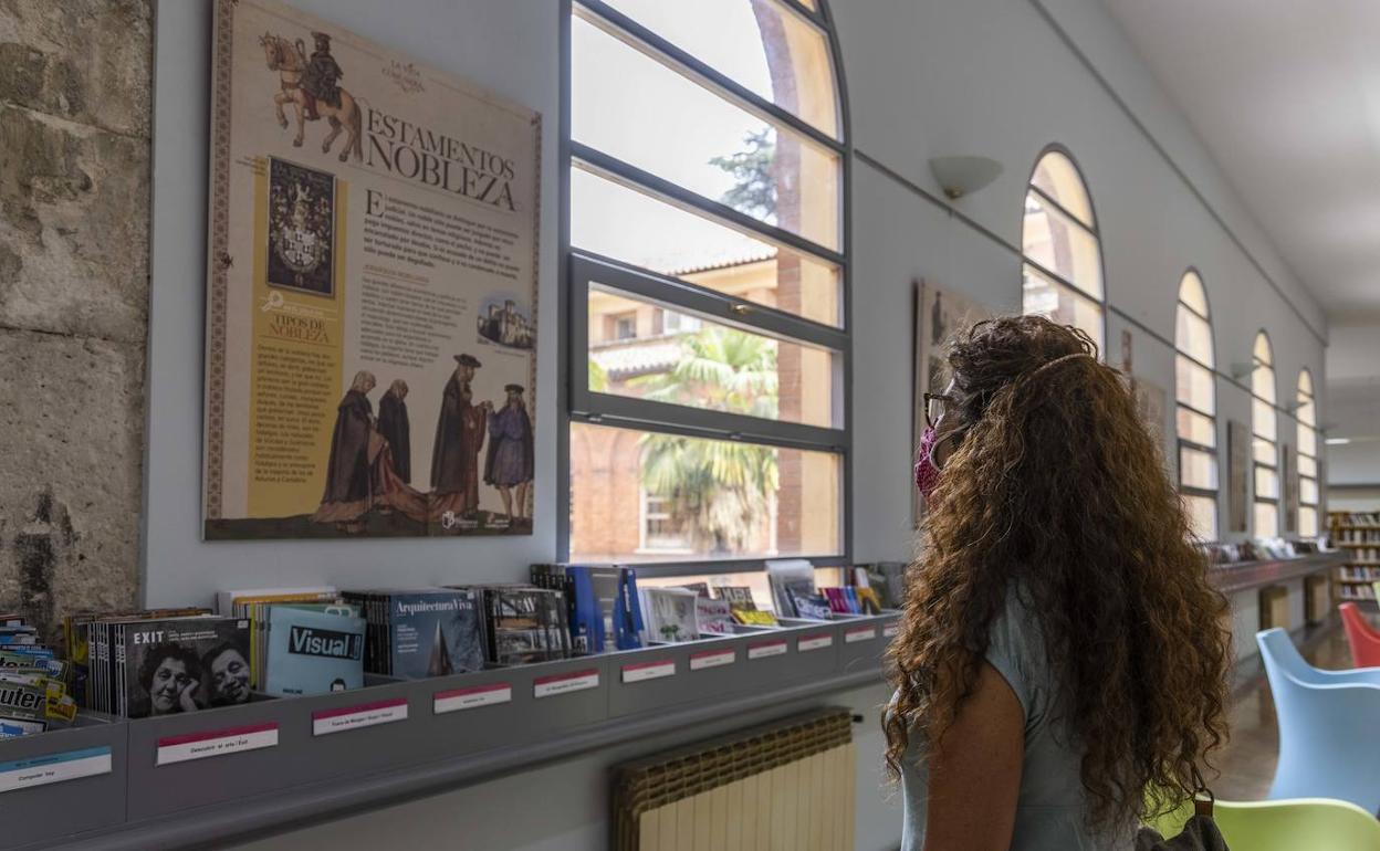 Una mujer contempla uno de los paneles de la exposición, en la sala de narrativa de la biblioteca. 